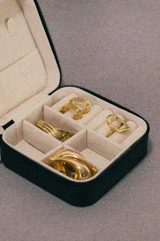 An open velvet jewellery case, gold rings set in its partitions.